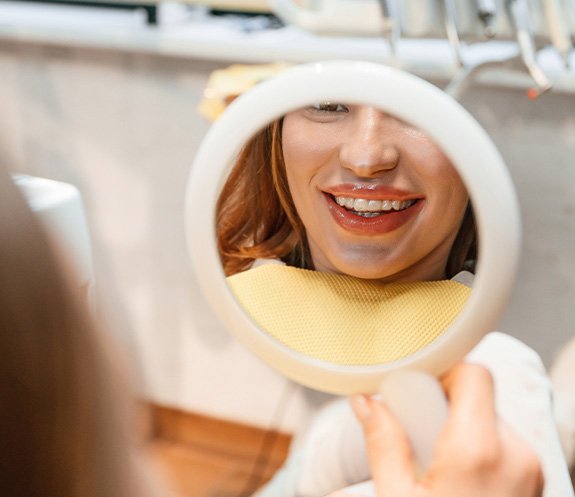 Patient with clear aligners smiling at reflection in mirror