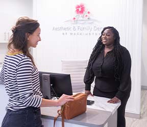 Friendly dental team member greeting patient at reception desk