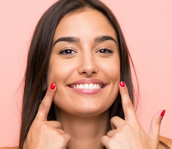 Woman pointing to bright smile after teeth whitening
