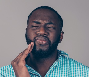 Man with toothache holding cheek in pain