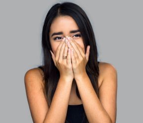 Woman with knocked out tooth covering her mouth