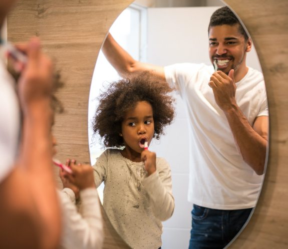 Father and child brushing teeth to prevent dental emergencies