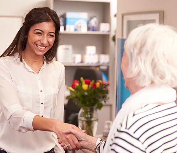 Dentist shaking hands with patient during dental implant consultation