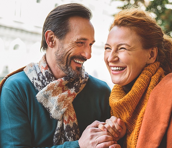 Couple smiling together after dental implant tooth replacement