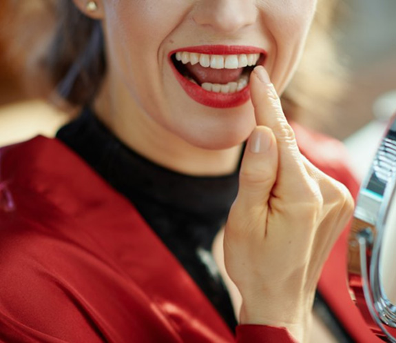 Woman examining her smile in a small mirror
