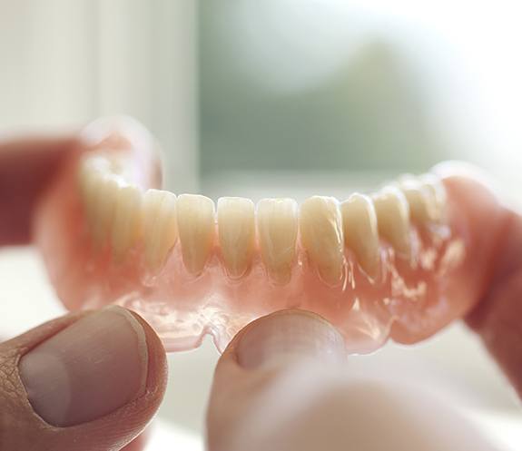 Hand holding full denture