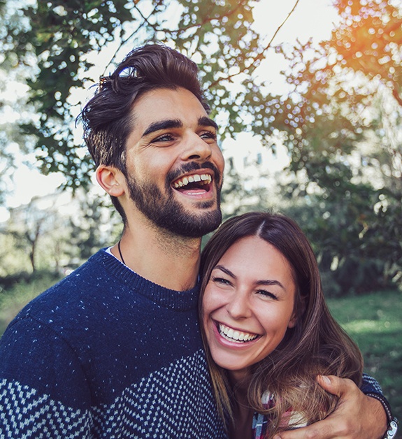 Man and woman with healthy smiles after periodontal disease treatment