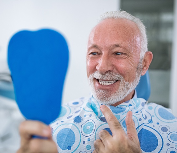 Man looking at his healthy smile after advanced treatment for periodontal disease