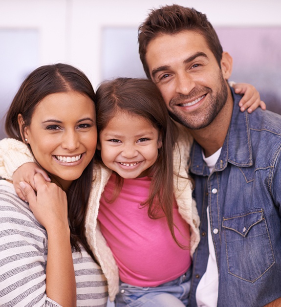 Parents and child smiling together after preventive dentistry