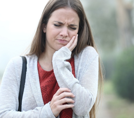 Woman in need of emergency dentistry holding cheek in pain