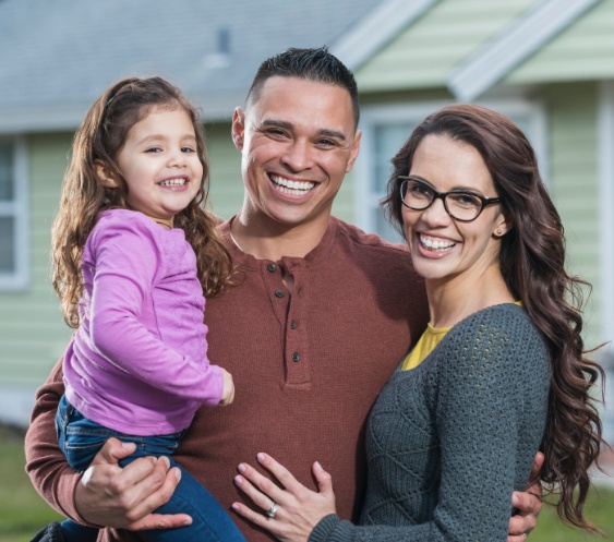 Parents holding child and smiling after children's dentistry