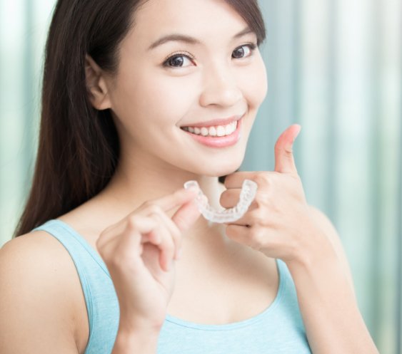 Woman holding an Invisalign clear braces tray