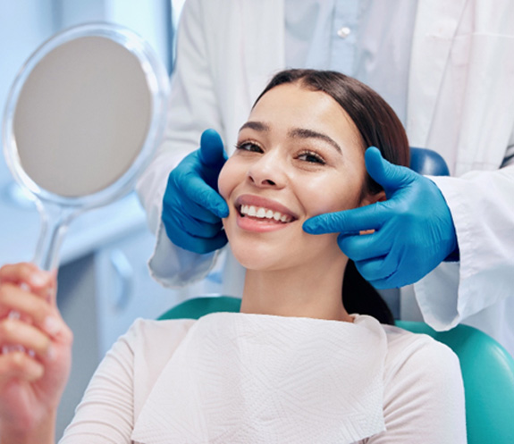 Patient smiling while holding small mirror