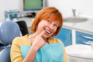 senior woman pointing to replacement tooth