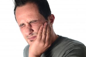 man holding his jaw in pain