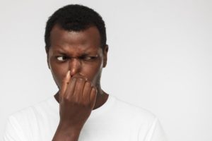 Man holding his nose after smelling bad breath