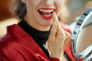 Woman inspecting her teeth for signs that they’ve shifted.