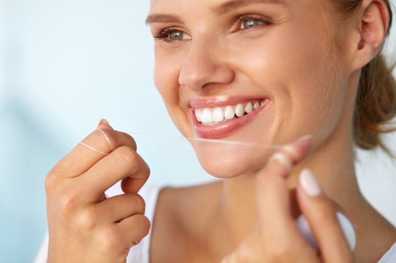 closeup of woman flossing her teeth 