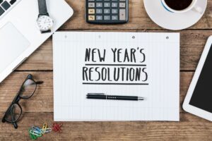 New Year's Resolutions written on lined paper next to other objects on a desk