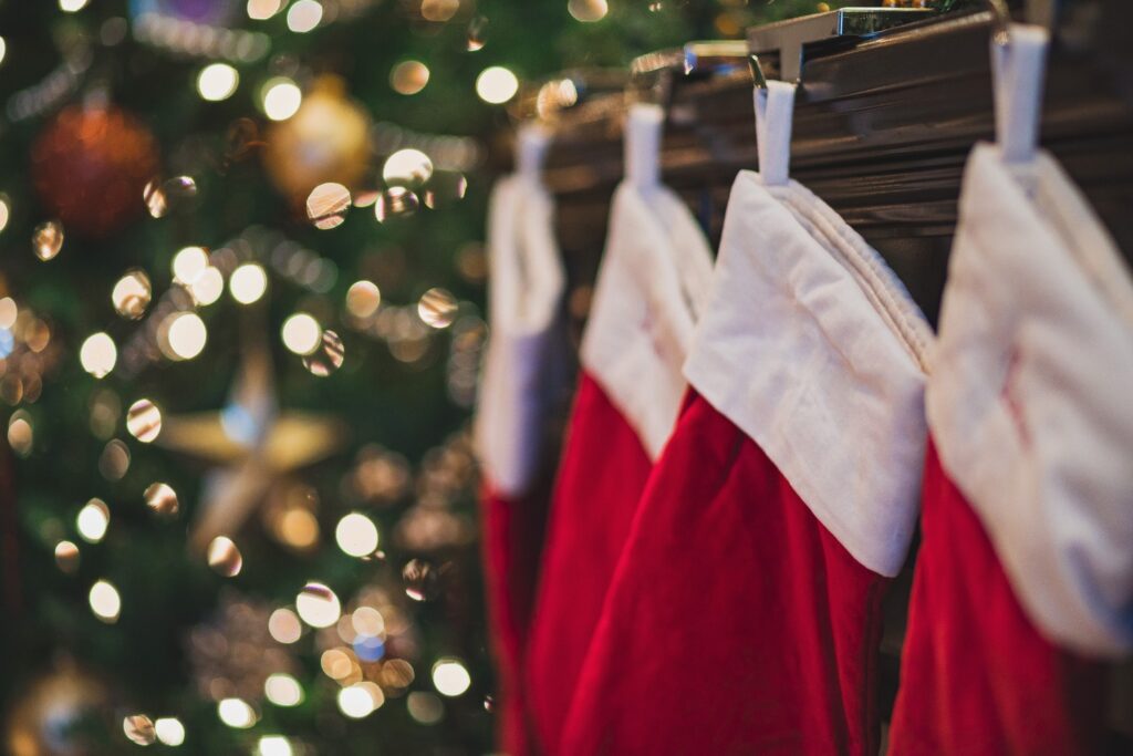 Red and white stockings hung on fireplace next to Christmas tree