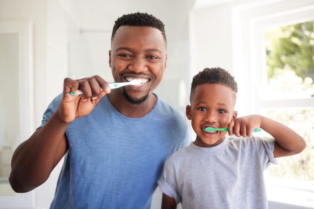 A father and son brushing their teeth.
